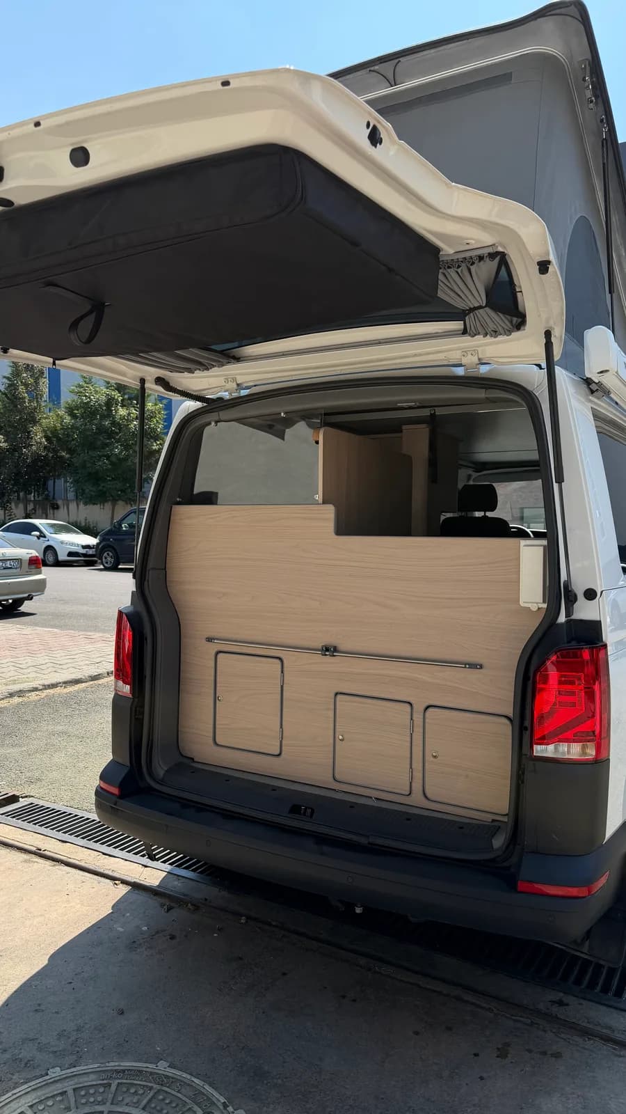 Geöffnete Heckklappe mit Holzwand des Badmoduls und Stauraumklappen
