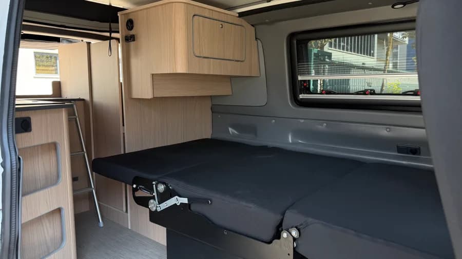 Innenraum mit umgeklappter Rückbank, Oberschrank und Leiter zum Dachbett