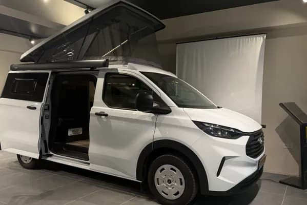 Beyaz Ford Transit Custom Assos — showroomda, SCA pop-up tavan açık ve yan kapı açık