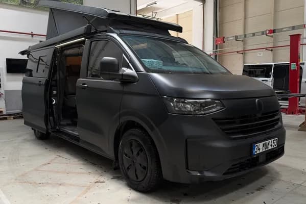 Mat siyah Volkswagen Transporter 4x4 Olympos — üretim tesisinde, SCA pop-up tavan ve yan kapı açık