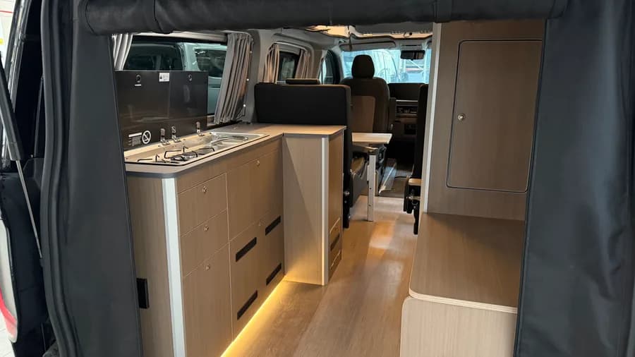 Innenraum mit Dometic-Kocher-Spülen-Einheit und LED-beleuchteten Holzmöbeln